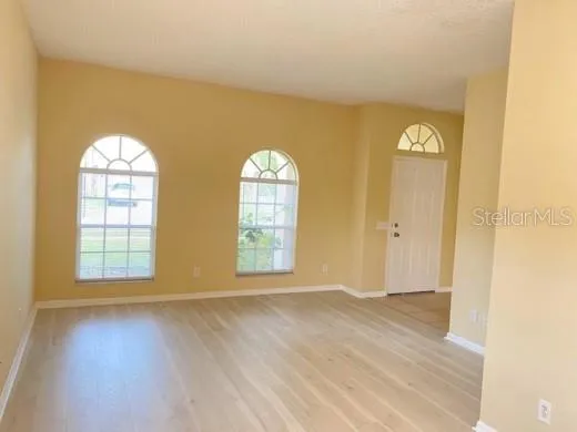 an empty room with windows and wooden floor