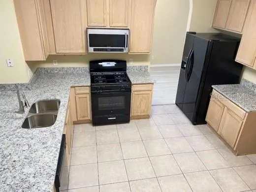 a kitchen with granite countertop a refrigerator and a stove top oven