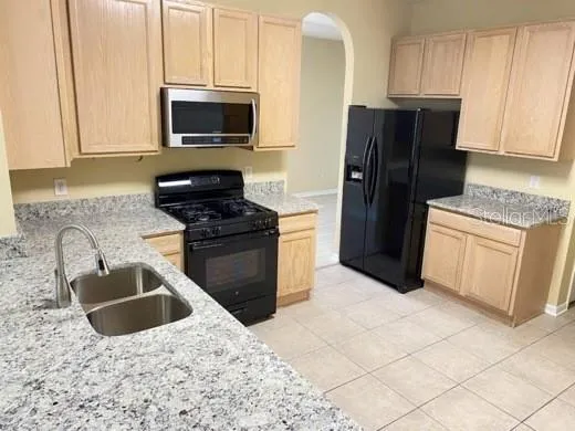 a kitchen with granite countertop a refrigerator stove and microwave