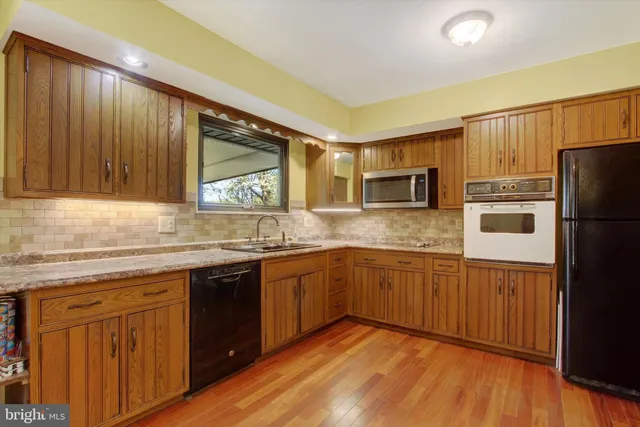 a kitchen with granite countertop stainless steel appliances a sink cabinets and wooden floor