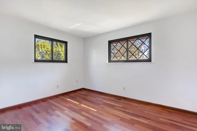 a view of an empty room with wooden floor and painting on the wall