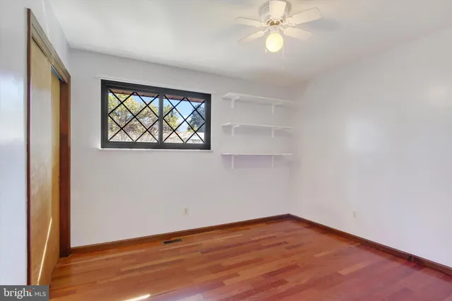 an empty room with wooden floor fan and windows
