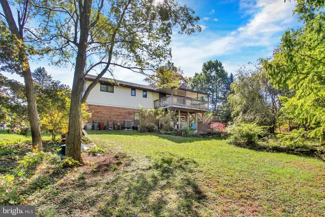 a view of a house with a yard and large trees