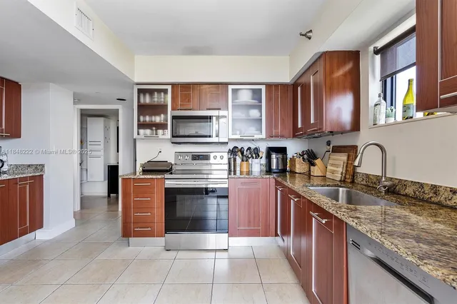 a kitchen with stainless steel appliances granite countertop a stove top oven a sink dishwasher and a refrigerator