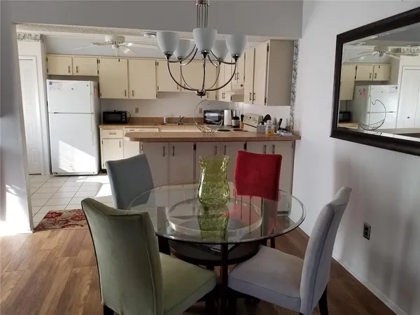 a view of a dining room with furniture a kitchen and chandelier