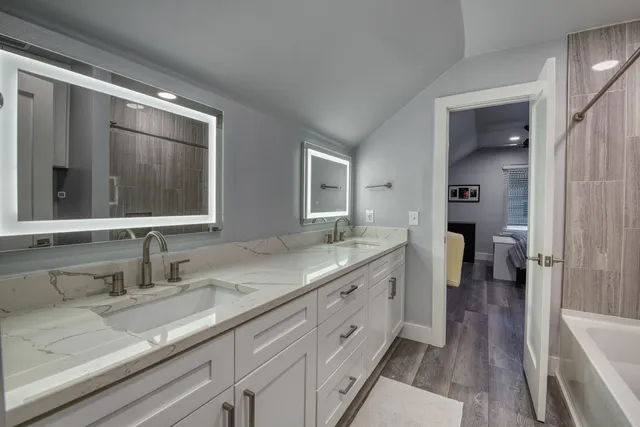a bathroom with a granite countertop double vanity sink and mirror