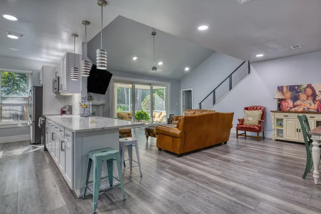 a living room with furniture kitchen view and a wooden floor