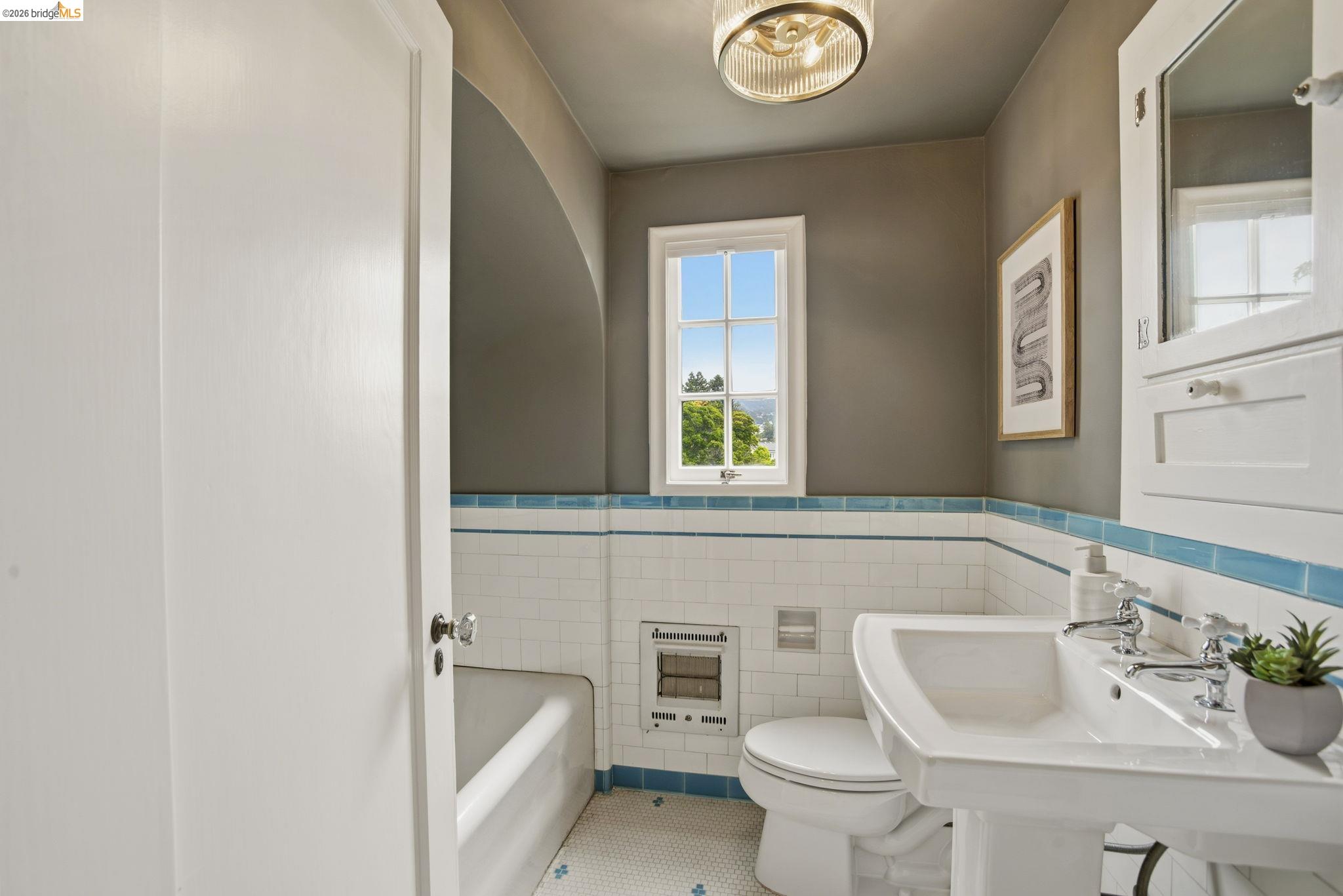 1087 Hubert Road Oakland, CA 94610 - Photo 34 of 67 Pedestal sink with chrome fixtures, subway tile wainscoting with blue accent trim, and a built-in medicine cabinet