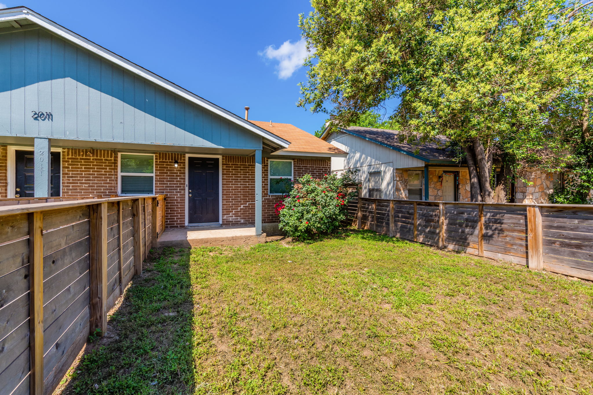2011 East Stassney Lane, Unit A Austin, TX 78744 - Photo 2 of 23 a view of a house with wooden fence and a large tree