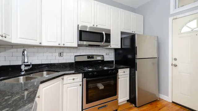 a kitchen with stainless steel appliances granite countertop white cabinets sink and a granite counter top