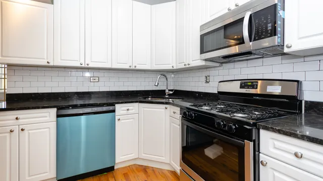a kitchen with granite countertop white cabinets and appliances