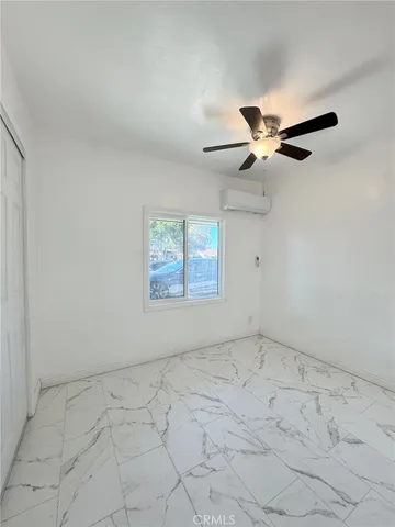 an empty room with a ceiling fan and window