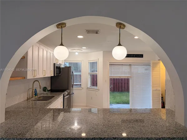 a kitchen with granite countertop a refrigerator and a stove top oven