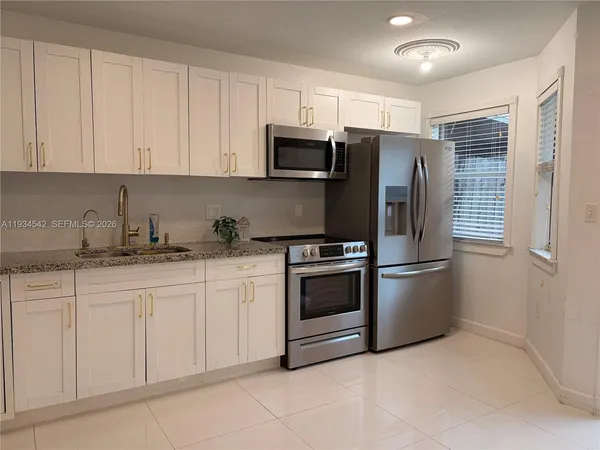 a kitchen with granite countertop white cabinets and stainless steel appliances