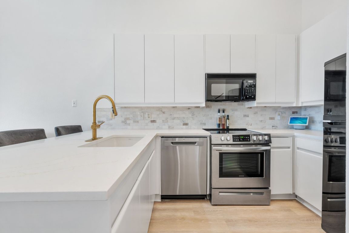 2918 Ranch Road 620, Unit 161 Austin, TX 78734 - Photo 10 of 35 a kitchen with stainless steel appliances granite countertop a stove a sink and a microwave