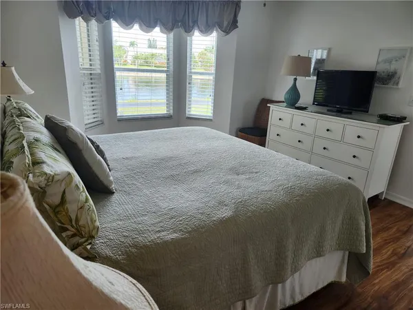 a bedroom with a bed and flat tv screen on the dresser