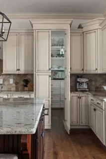 a kitchen with kitchen island granite countertop a stove a sink and white cabinets