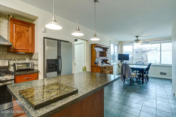 a kitchen with stainless steel appliances granite countertop a stove top oven a sink table and chairs