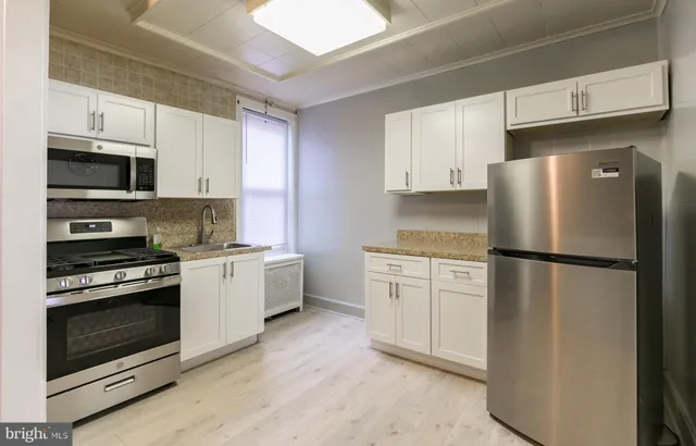 a kitchen with stainless steel appliances white cabinets white stove a microwave and a refrigerator