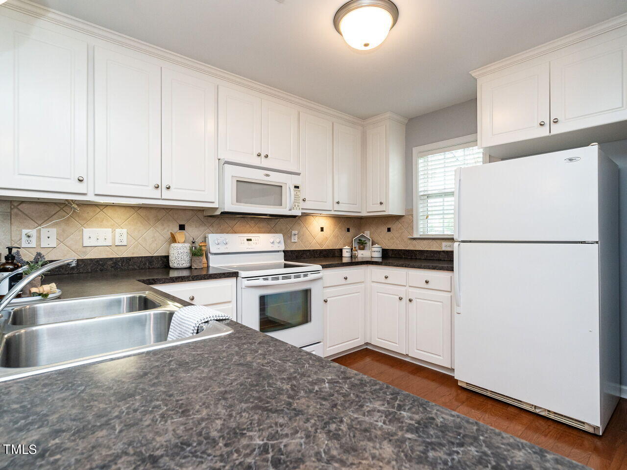 585 Pinecroft Drive Clayton, NC 27520 - Photo 5 of 26 a kitchen with granite countertop a refrigerator sink stove and white cabinets