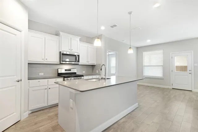 a kitchen with stainless steel appliances granite countertop a sink a stove and a wooden floors