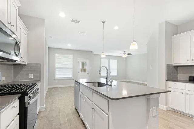 a kitchen with stainless steel appliances a sink a stove a refrigerator and cabinets