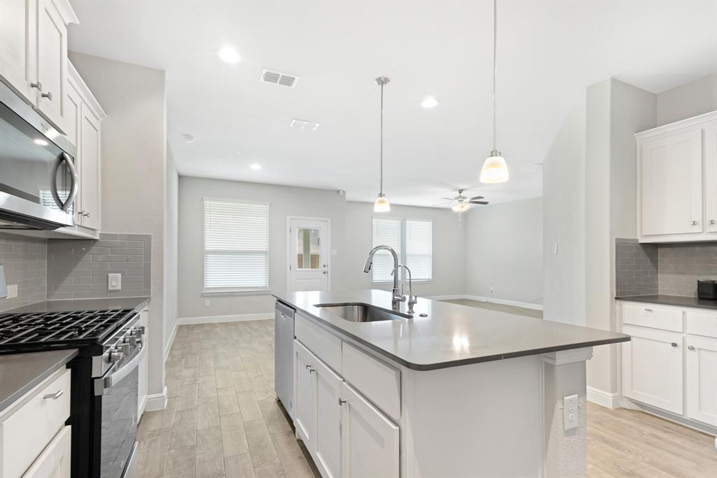 820 Wilmott Terrace Justin, TX 76247 - Photo 7 of 22 a kitchen with stainless steel appliances granite countertop a sink a stove and a wooden floors