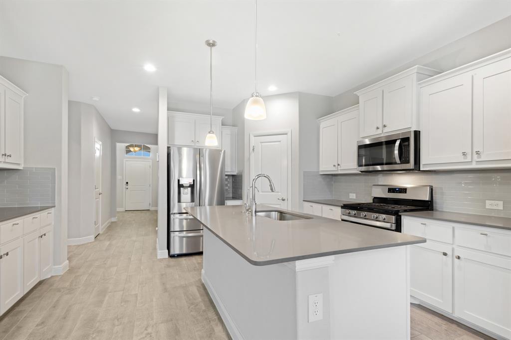 820 Wilmott Terrace Justin, TX 76247 - Photo 8 of 22 a kitchen with stainless steel appliances a sink a stove a refrigerator and cabinets
