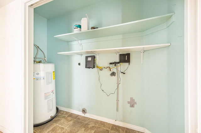 161 West 950 South, Unit C5 St. George, UT 84770 - Photo 11 of 14 Utility closet featuring a water heater, two wall-mounted storage shelves, and durable vinyl flooring