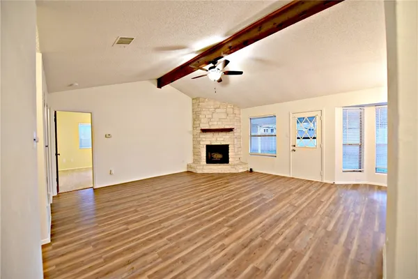 a view of empty room with wooden floor and fireplace