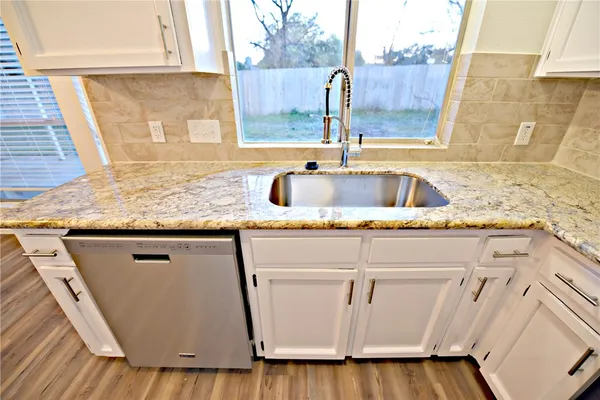 a kitchen with granite countertop a sink and a wooden floor