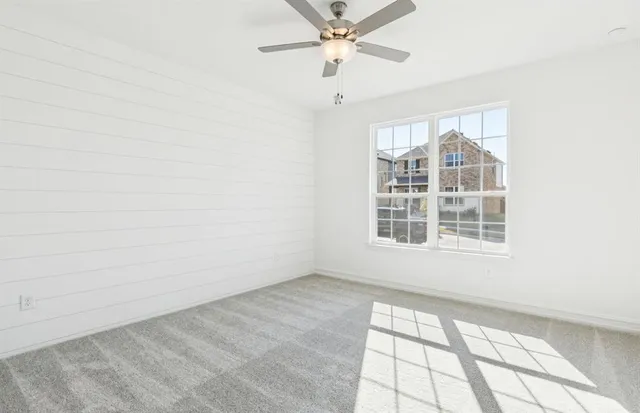an empty room with window and ceiling fan