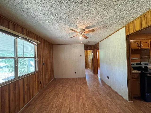 a view of empty room with wooden floor and fan