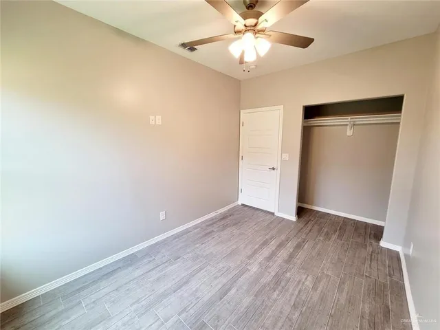 an empty room with wooden floor and ceiling fan