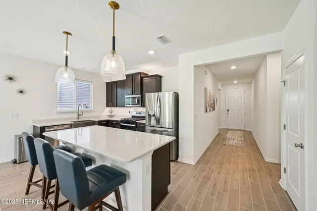 a kitchen with stainless steel appliances granite countertop a kitchen island a stove a refrigerator and a view of living room