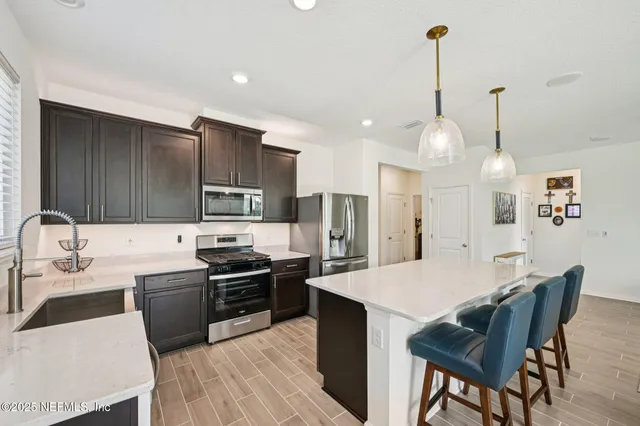 a kitchen with stainless steel appliances kitchen island granite countertop a sink a stove a refrigerator and island
