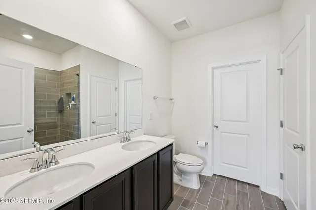 a bathroom with a granite countertop sink toilet a large mirror and shower