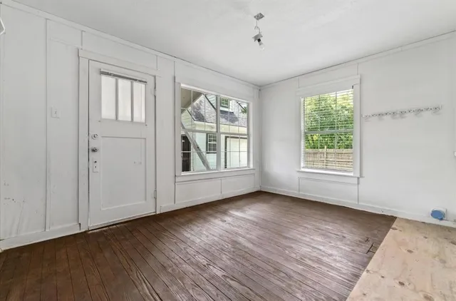 a view of an empty room with wooden floor and a window