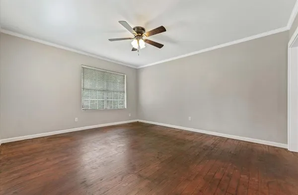 an empty room with wooden floor fan and windows