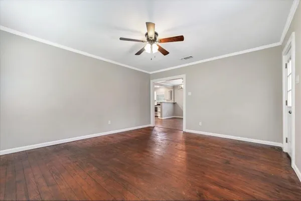 an empty room with wooden floor ceiling fan and windows