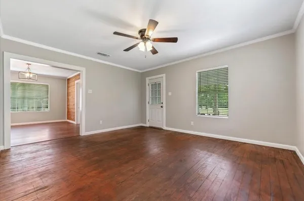 a view of empty room with wooden floor and fan