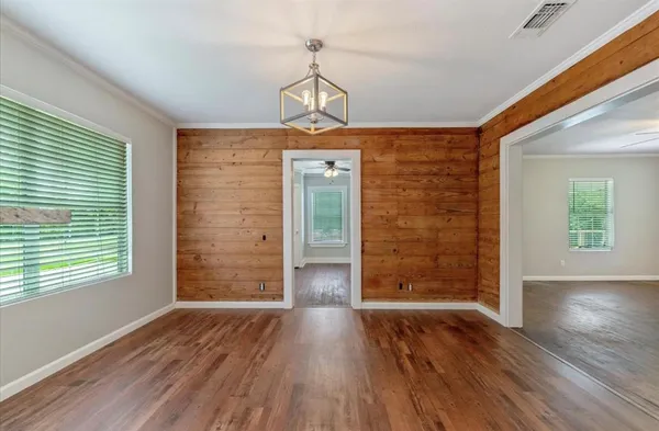 an empty room with wooden floor chandelier and windows
