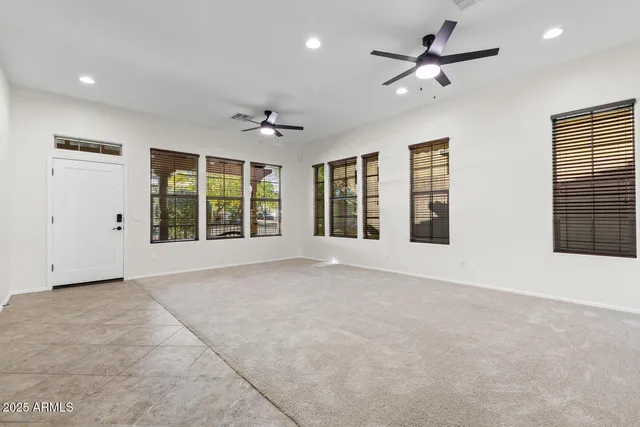a view of an empty room with a window and a kitchen