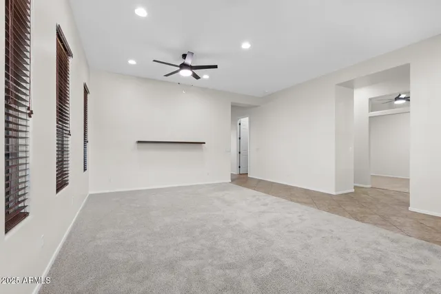 an empty room with a ceiling fan and windows