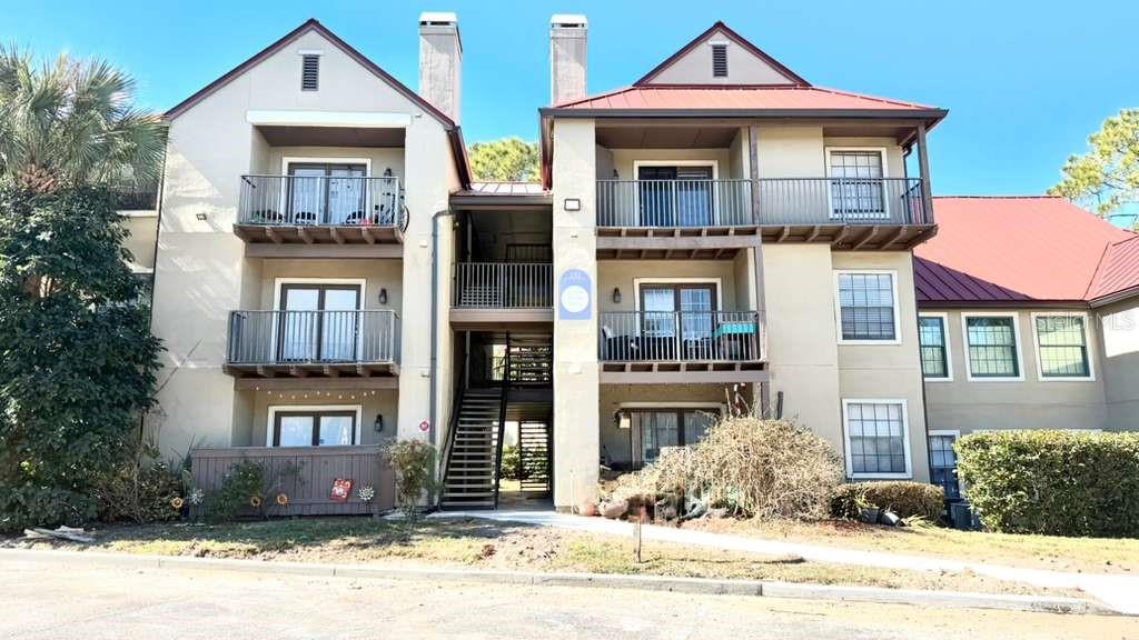 a front view of a residential apartment building with a yard and parking space