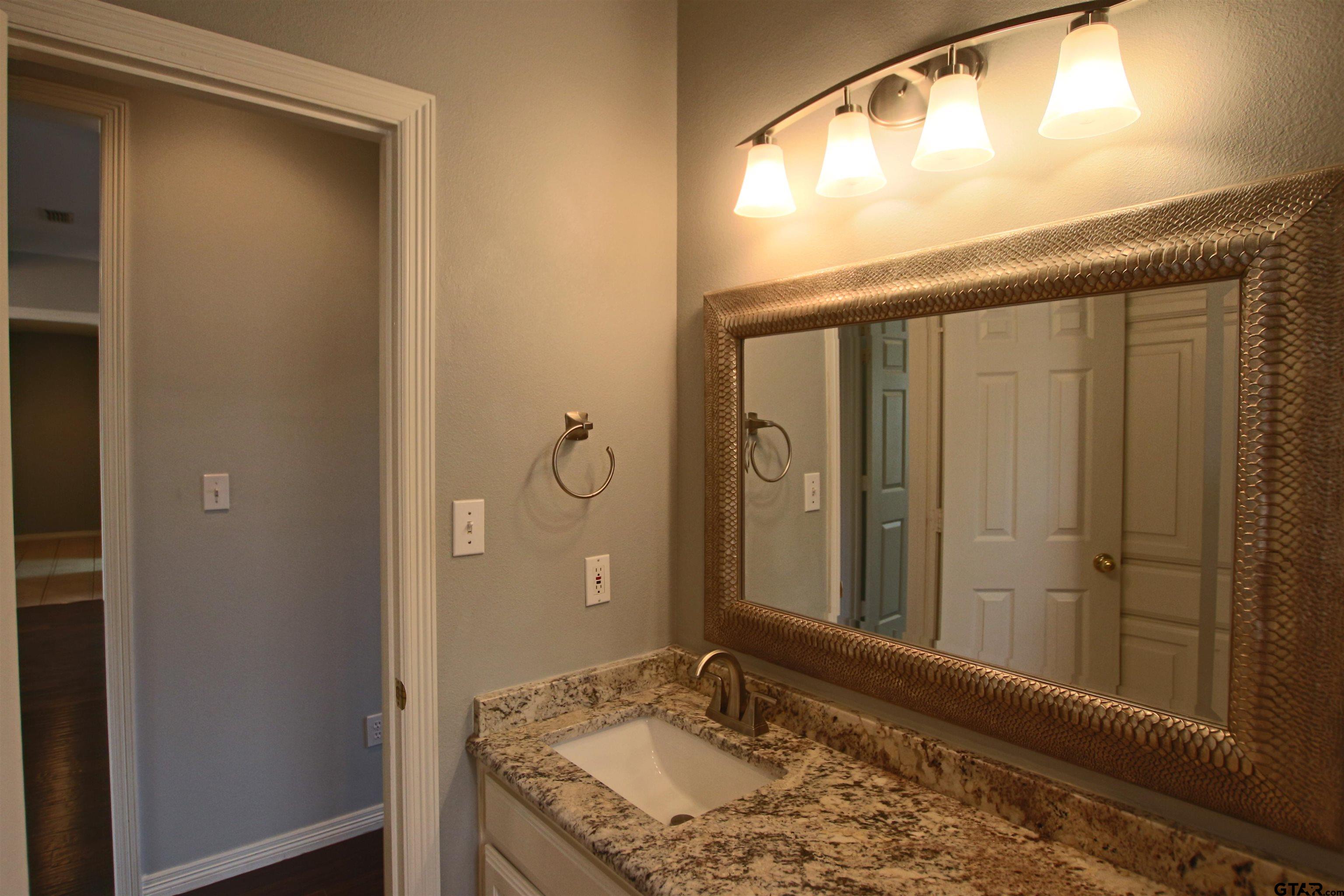 5707 Nicholson Drive Tyler, TX 75707 - Photo 21 of 23 a bathroom with a granite countertop sink and a mirror