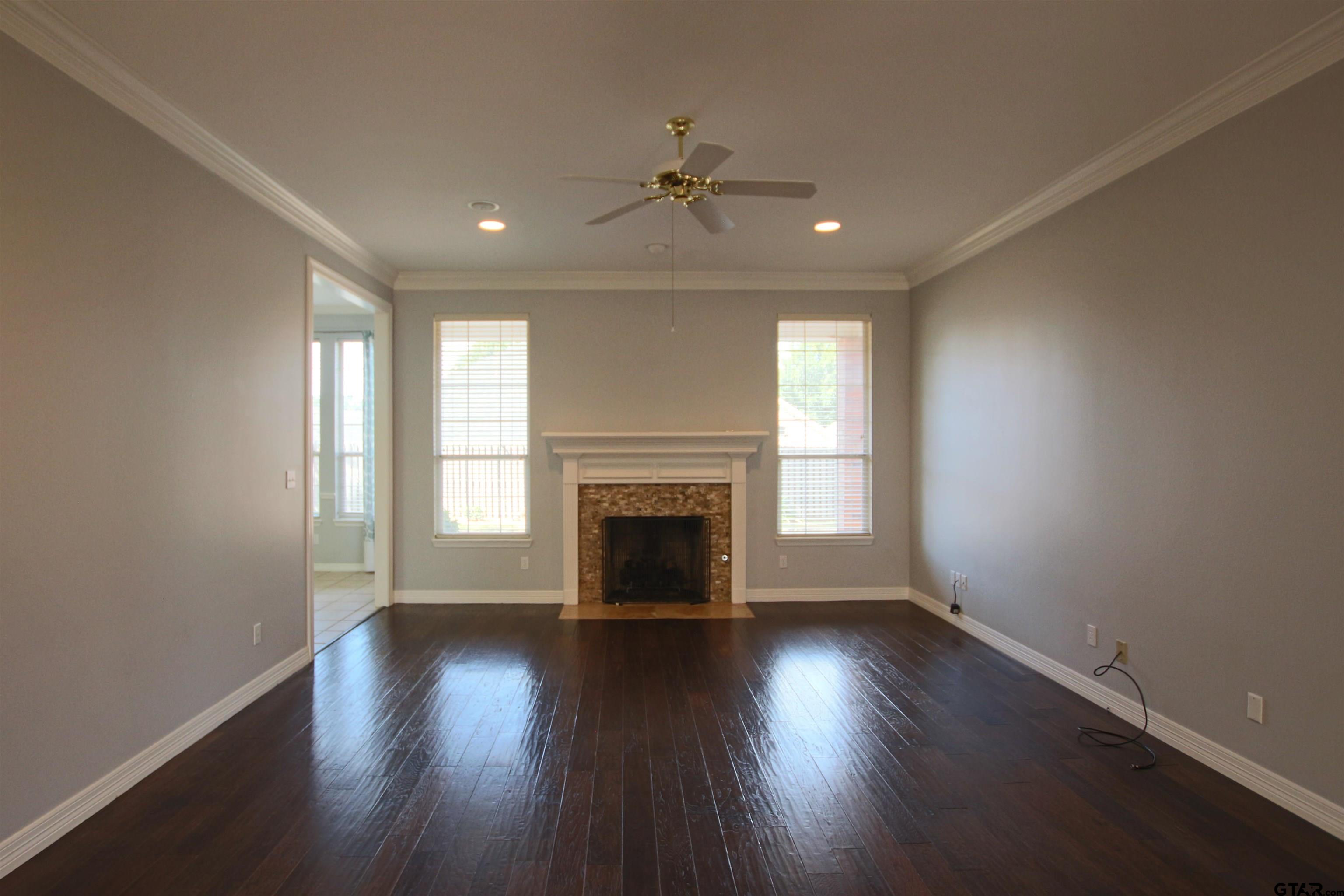 5707 Nicholson Drive Tyler, TX 75707 - Photo 4 of 23 an empty room with wooden floor fireplace and windows