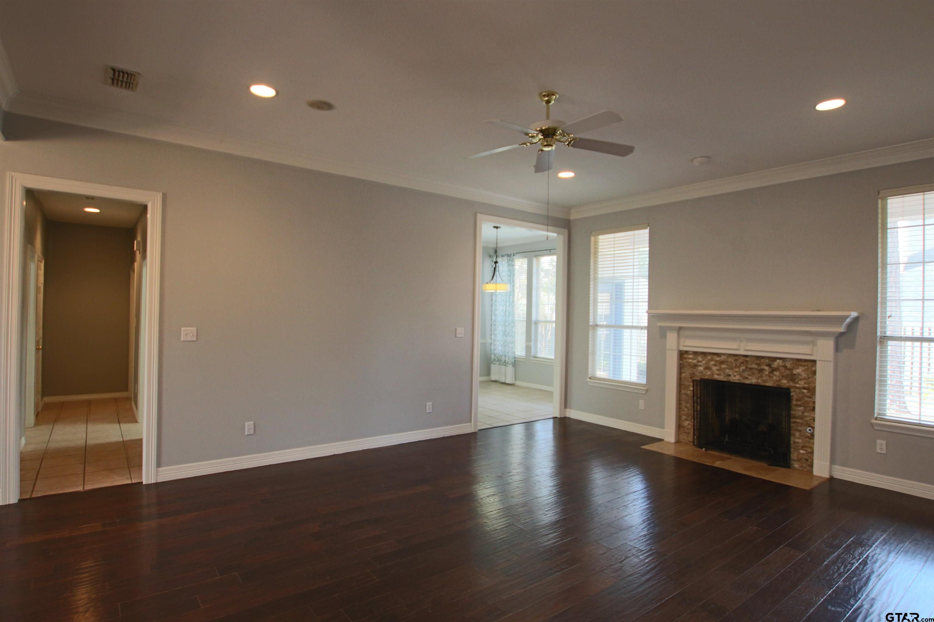 5707 Nicholson Drive Tyler, TX 75707 - Photo 5 of 23 an empty room with wooden floor fireplace and windows