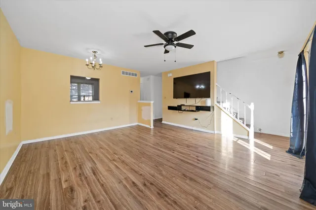 a view of a livingroom with a flat screen tv wooden floor and a ceiling fan