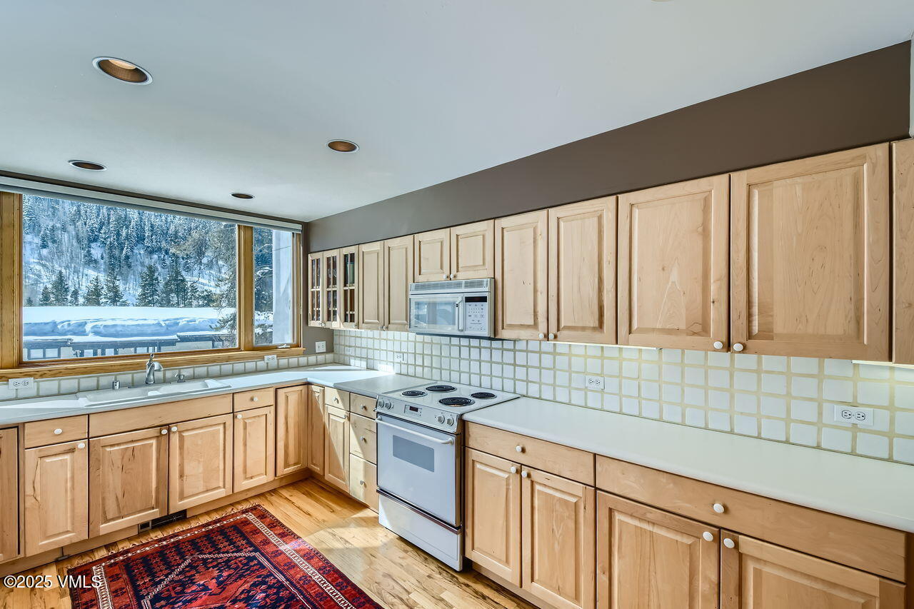 4173 Spruce Way Vail, CO 81657 - Photo 8 of 29 a kitchen with stainless steel appliances a stove sink and cabinets